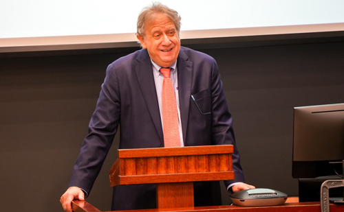 Brooklyn Law School Professor Michael Gerber smiles while speaking from behind a podium.