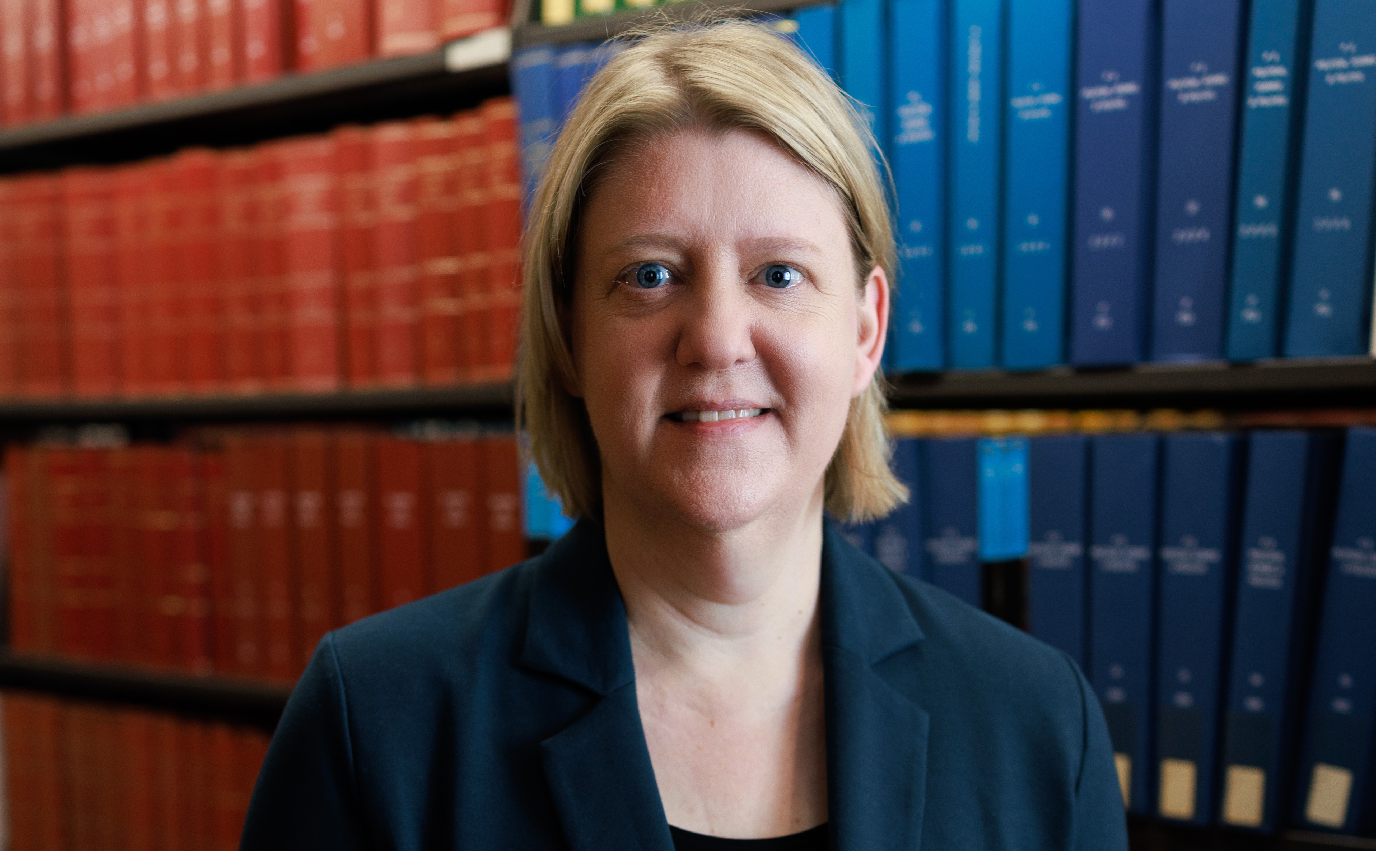A woman standing in front of a bookcase.