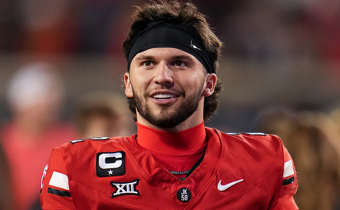 A man in a red football jersey wearing a black headband and no helmet.