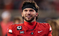 A man in a red football jersey wearing a black headband and no helmet.