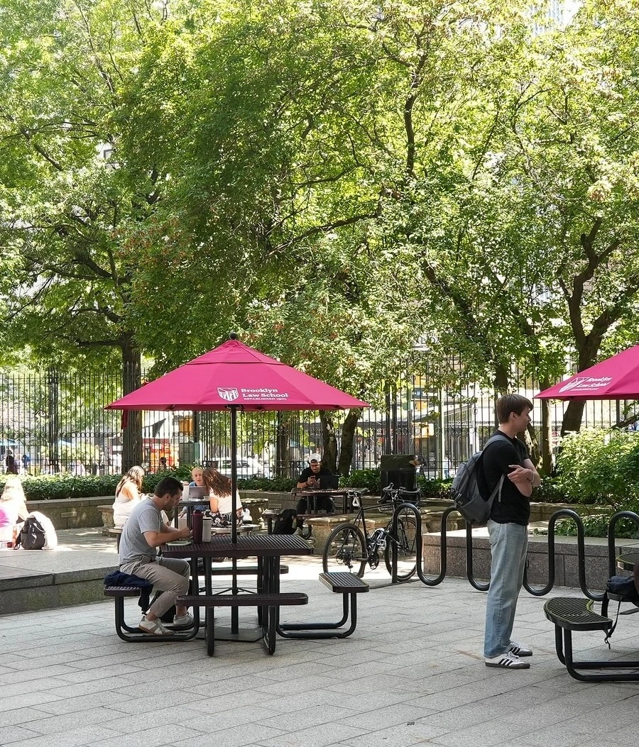 a wide view of people sitting at tables under sun umbrellas