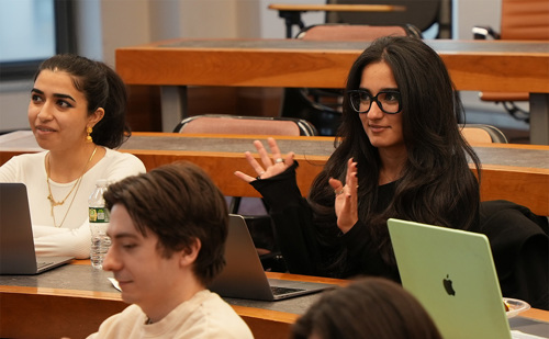 Three Brooklyn Law School students sit in a lecture hall with laptops.