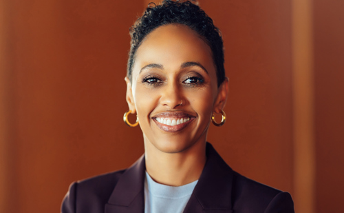 A woman with short hair with a faded brown background.