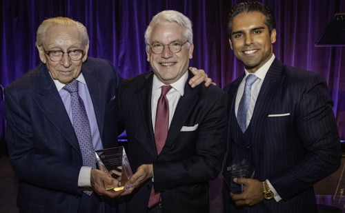 Three men in suits and ties pose for a picture, with Larry Silverstein on the left holding a glass trophy, and Ankit Kapoor on the right holding a trophy, with David Meyer in the middle.