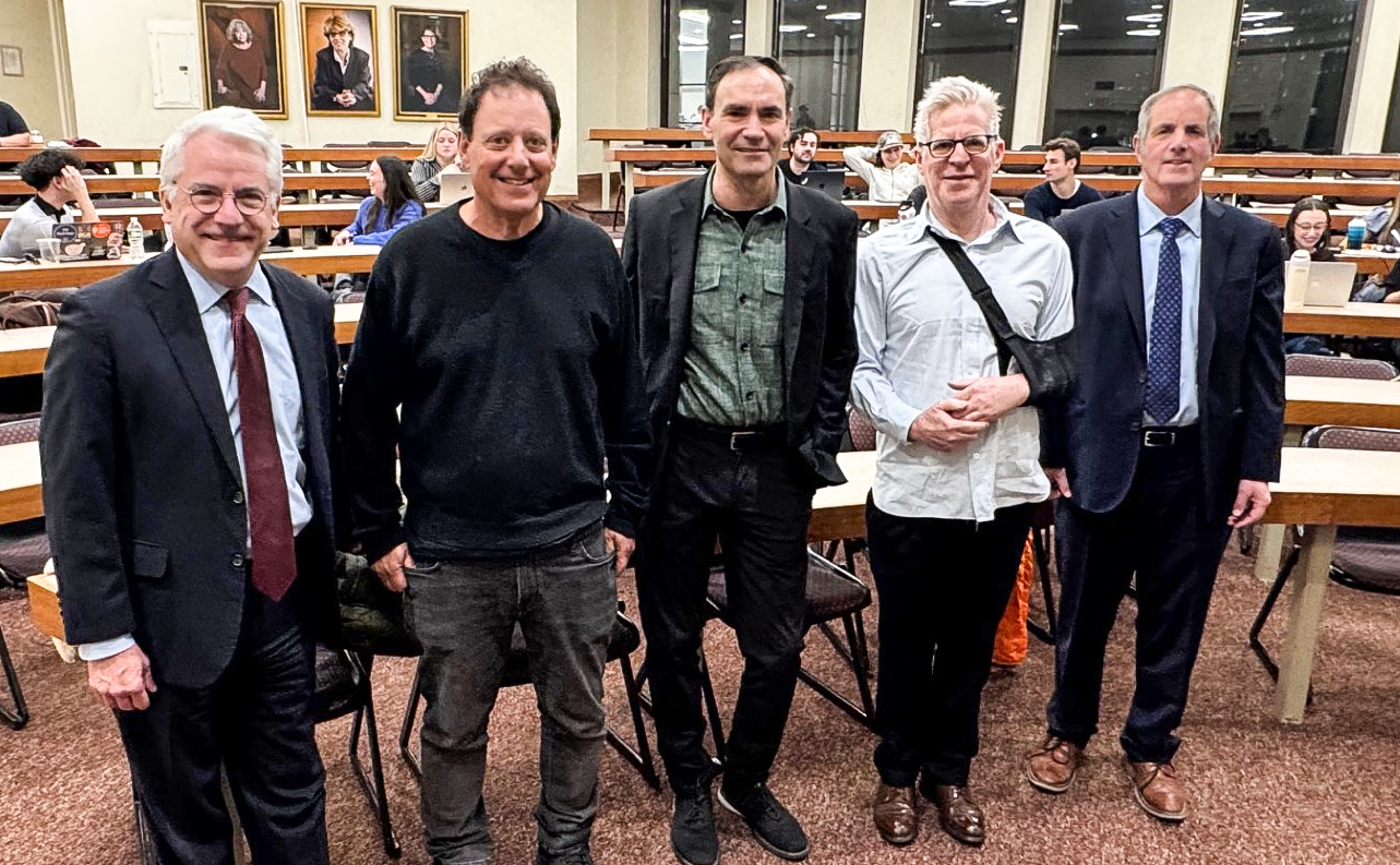 Five men pose together in the front of a large room on the campus of Brooklyn Law School.