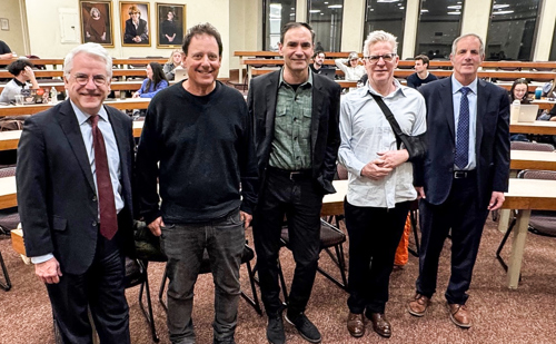 Five men pose together in the front of a large room on the campus of Brooklyn Law School.