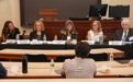 A five-person panel sits at a table and takes questions from students in a classroom.