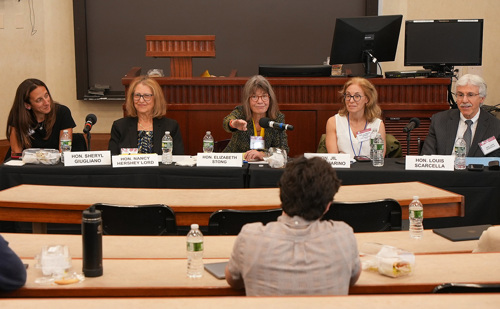 A five-person panel sits at a table and takes questions from students in a classroom.