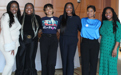 Six members of the Women of COlor Alliance pose together in a large room on the campus of Brooklyn Law School.