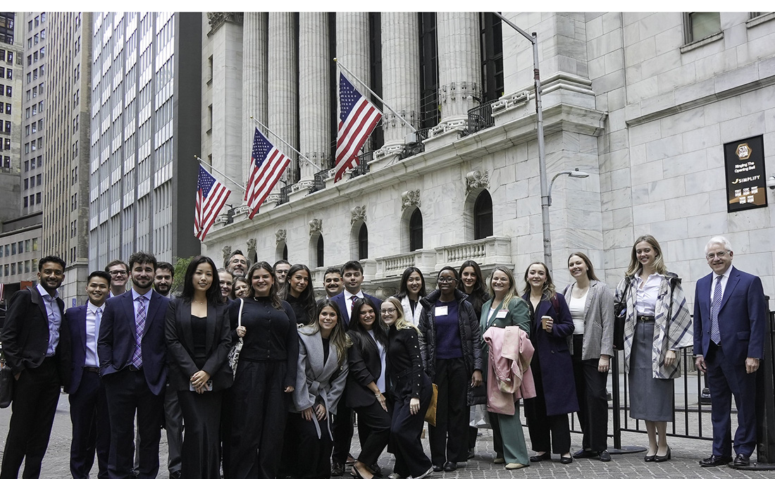 A large group of formally dressed people pose outside of the New York Stock Exchange building in New York City.