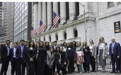 A large group of formally dressed people pose outside of the New York Stock Exchange building in New York City.