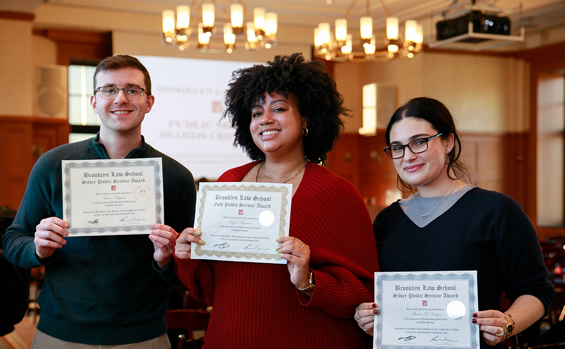 Three students holding up certificates from Brooklyn Law School.