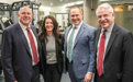 Four people, three men and one woman, pose for a picture in the new fitness center inside Feil Hall at Brooklyn Law School.