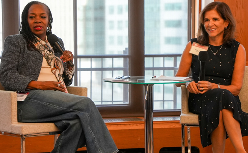 Brooklyn Law School professor Jodi Balsam sits to the right of a glass table with Stephanie Hightower on the other side of the table during a symposium.