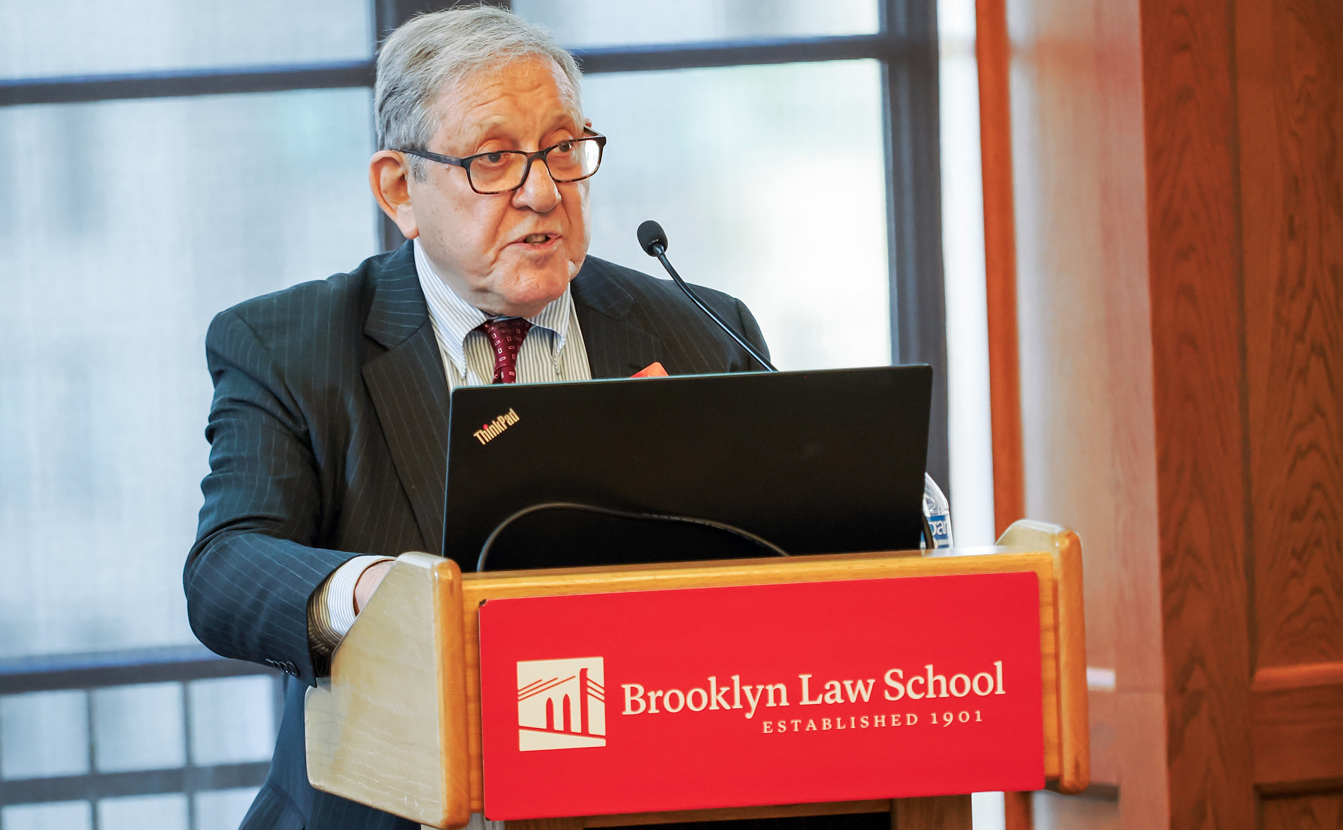 Brooklyn Law School Professor Joel Gora speaks behind a lectern with Brooklyn Law School branding.