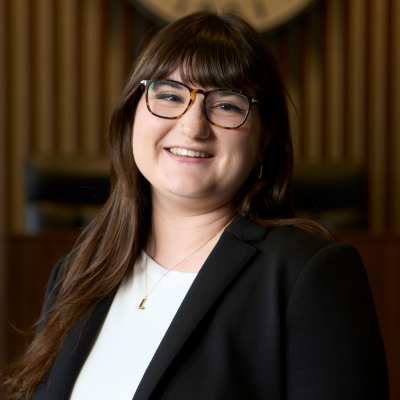 Photo of Katherine Eliou, woman with glasses and suit jacket and long hair
