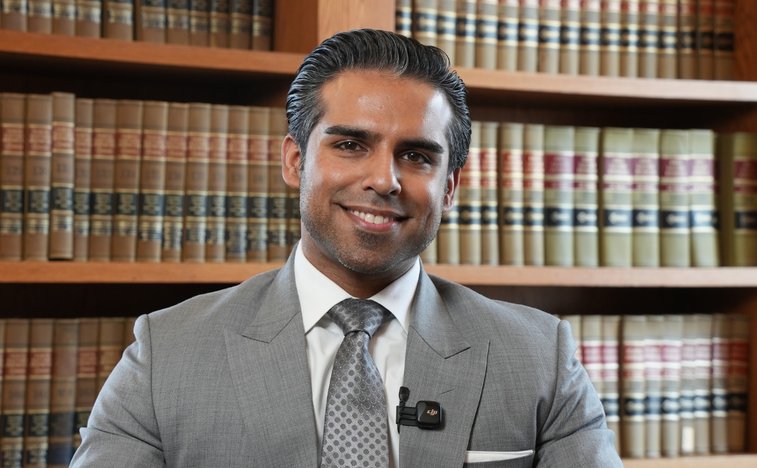 Ankit - Man in grey suit with grey tie in front of book case