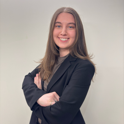 Photo of Maire Gordon, a with woman crossed arms, long hair, suit jacket